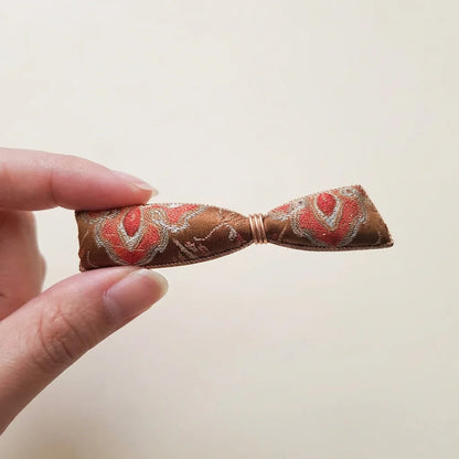 Bow Silk Brocade Hair Clip — Terracotta held in fingertips SIZE scale reference